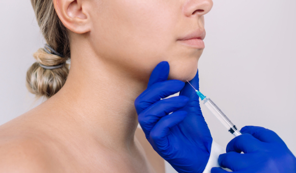 Close-up of a woman receiving an injection in her chin, focusing on the precision and care