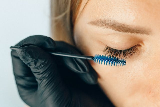 Close-up of a woman's eye with someone holding a spoolie brush