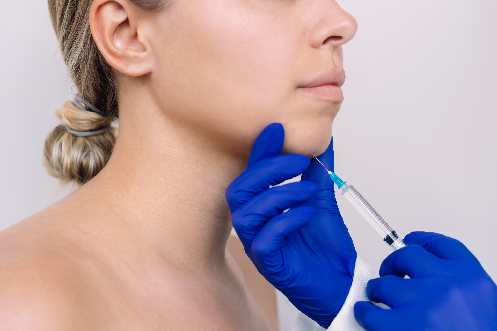 Close-up of a woman receiving an injection in her chin, focusing on the precision and care